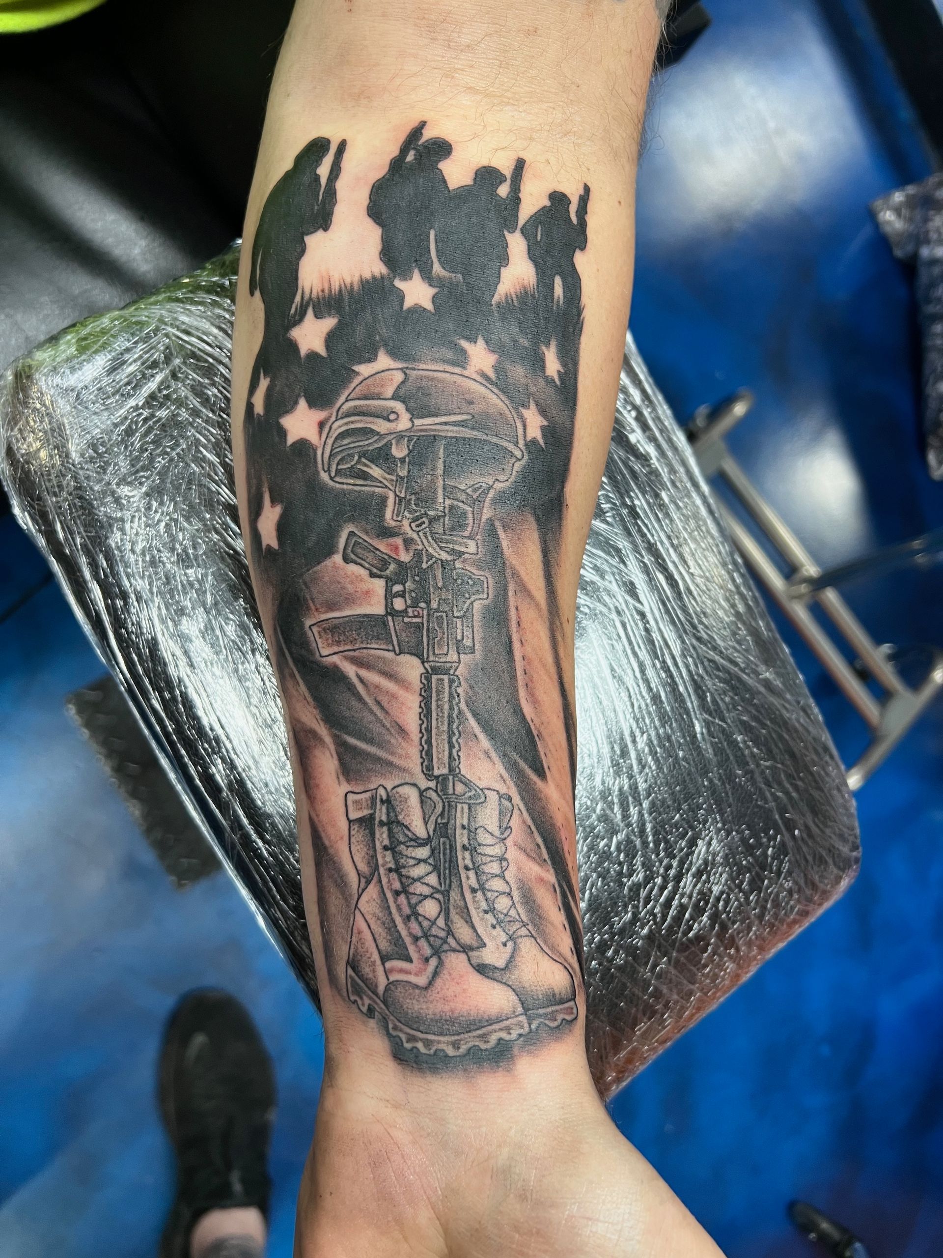 A man has a tattoo of an american flag and a cross on his forearm