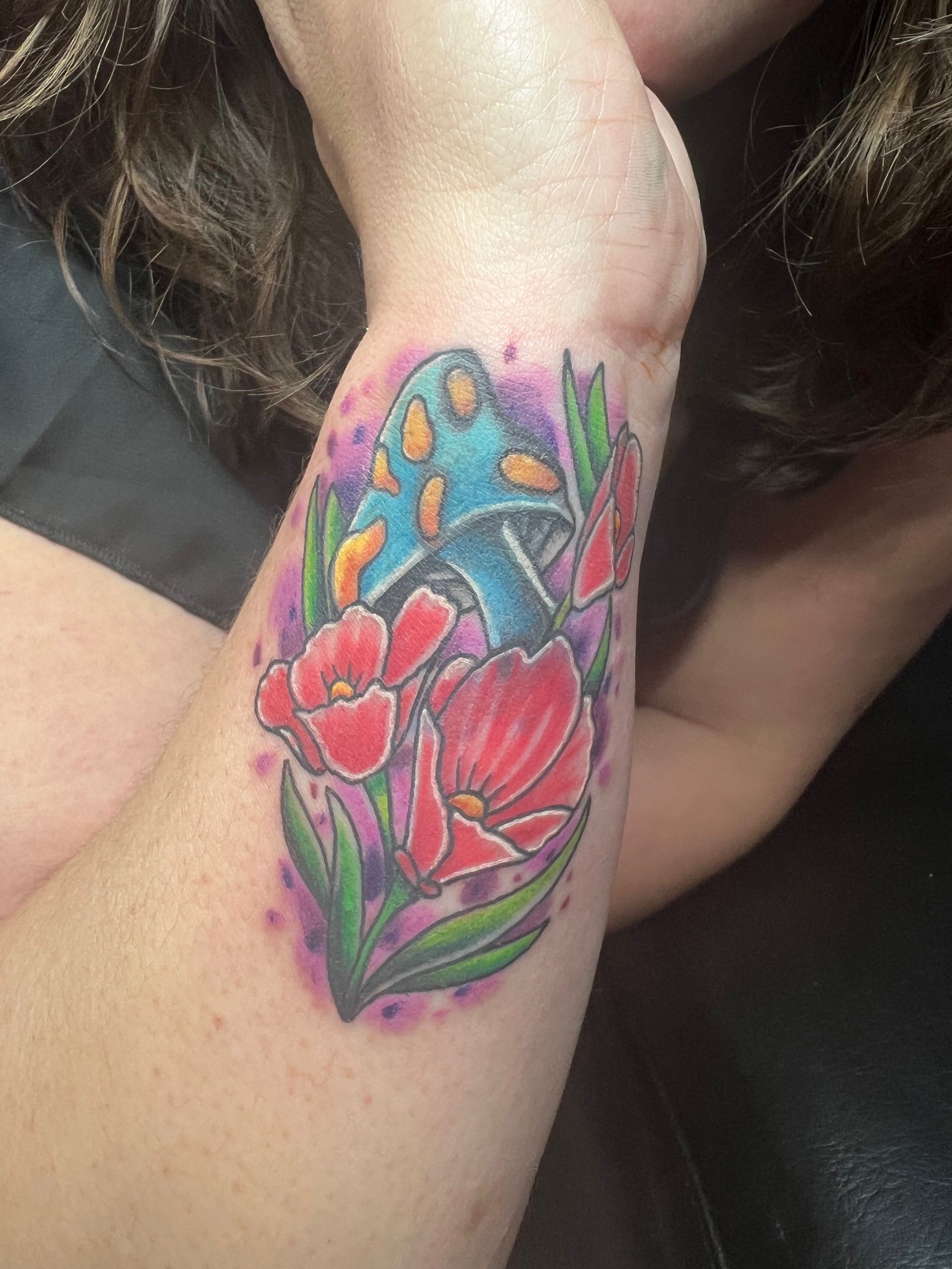 A woman has a tattoo of a mushroom and flowers on her arm.
