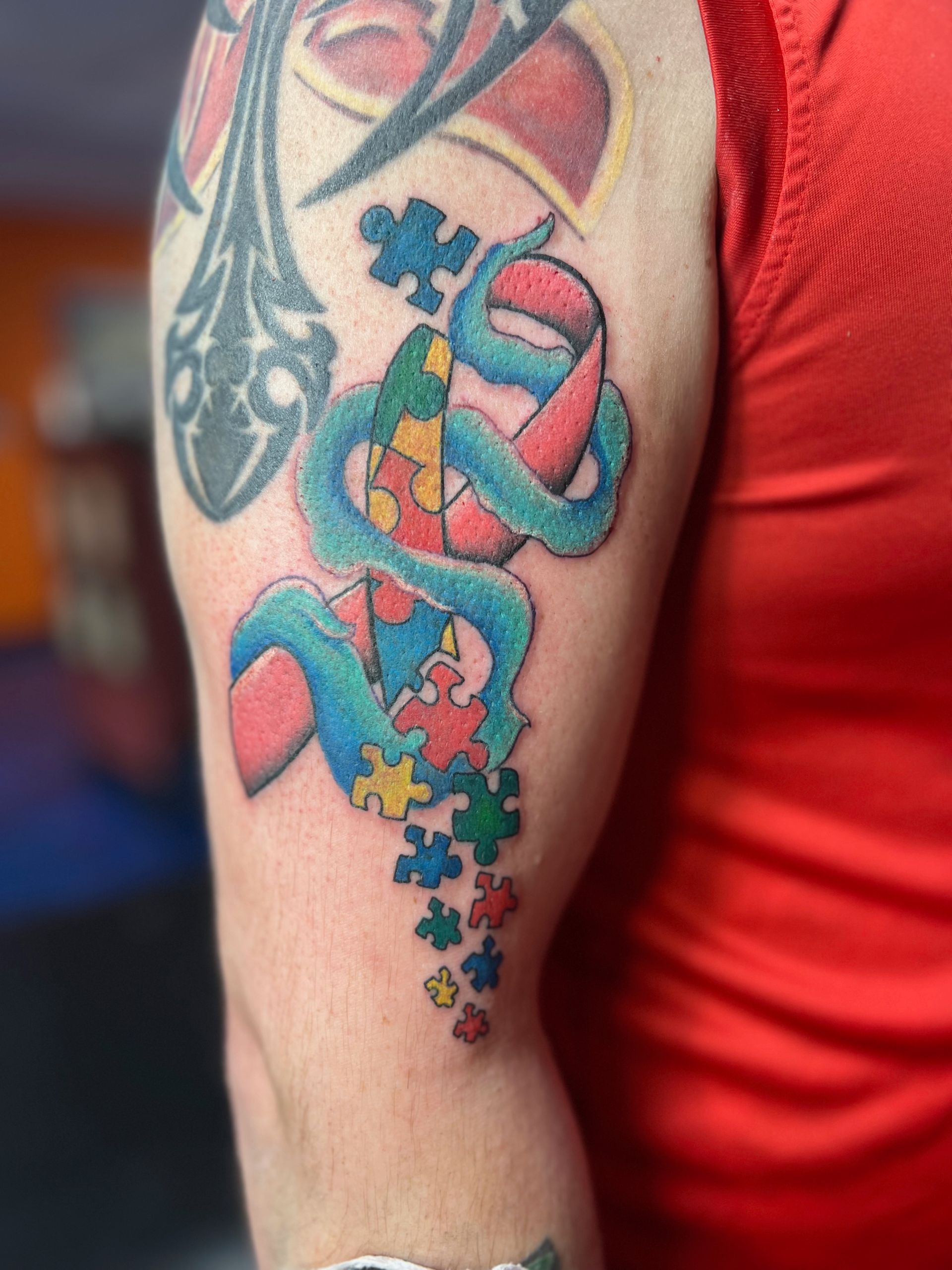 A person has a tattoo of a snake and puzzle pieces on their arm.