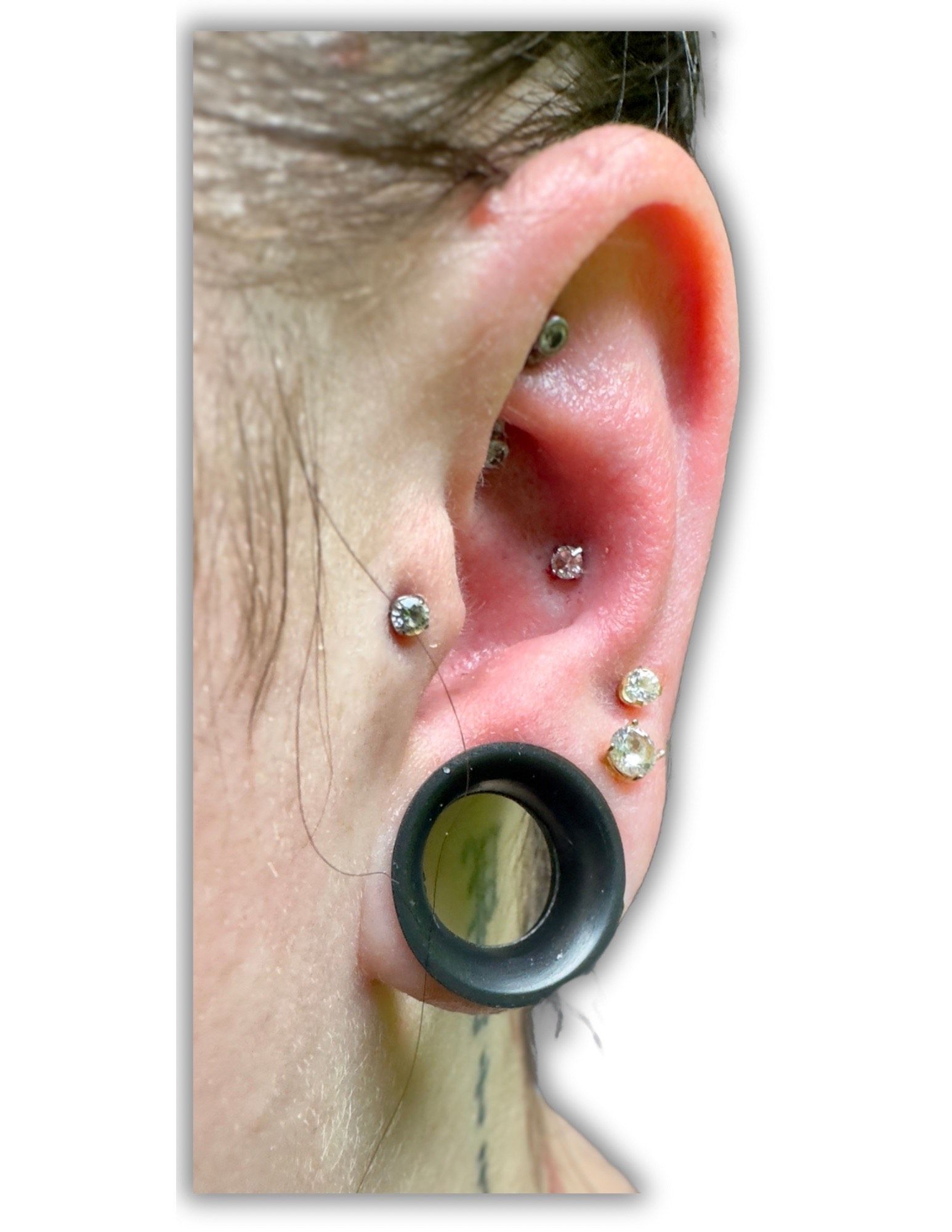 A close up of a person 's ear with multiple piercings.