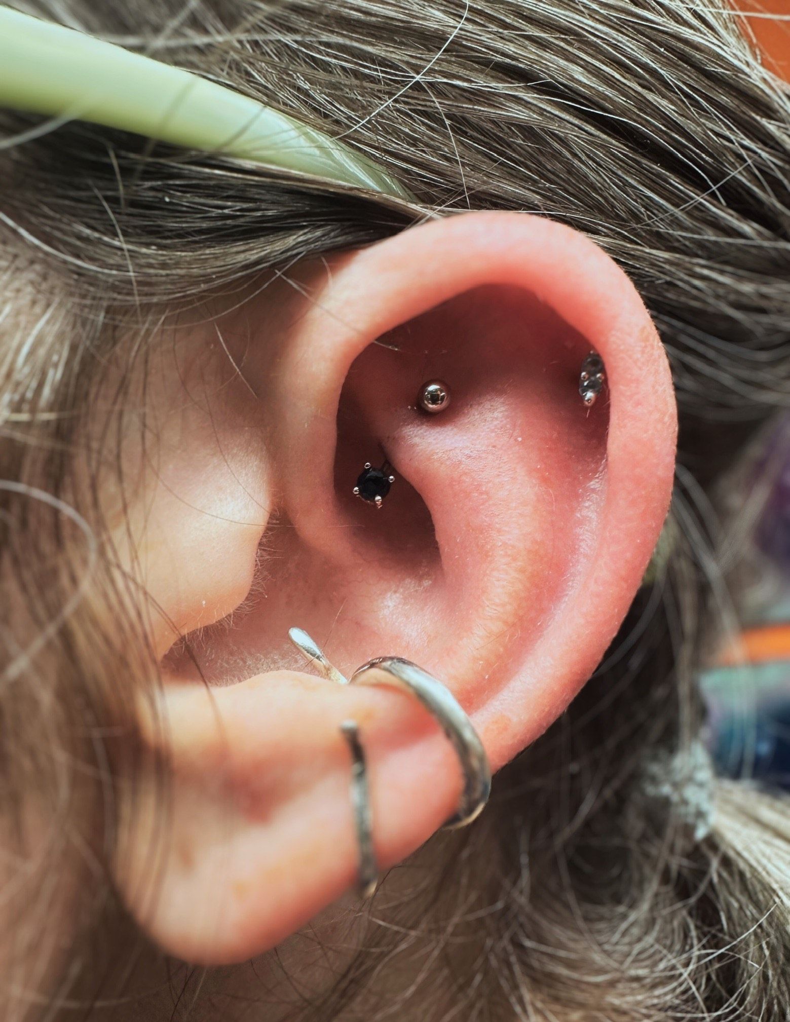 A close up of a woman 's ear with multiple piercings.