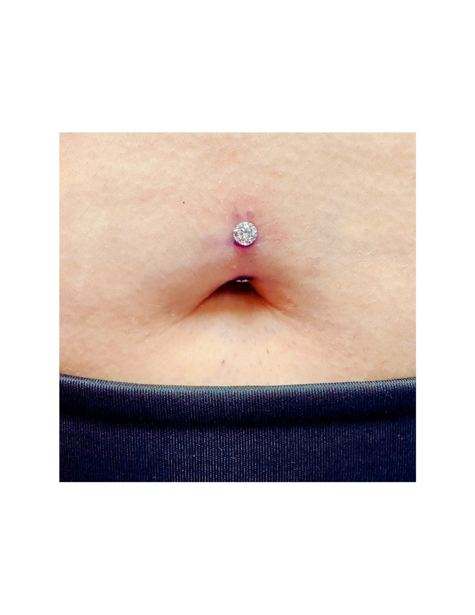 A close up of a woman 's belly with a belly button ring.