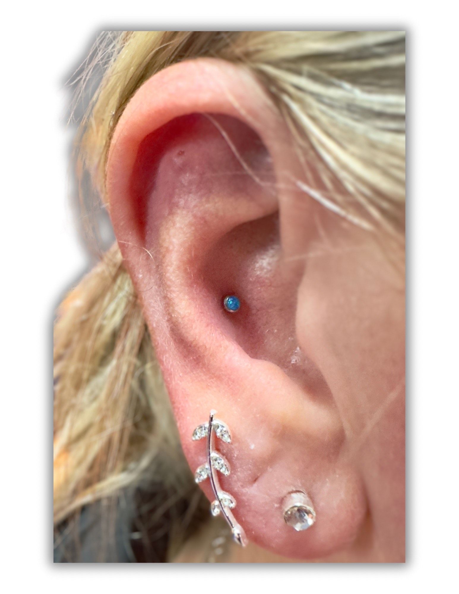A close up of a woman 's ear with multiple piercings