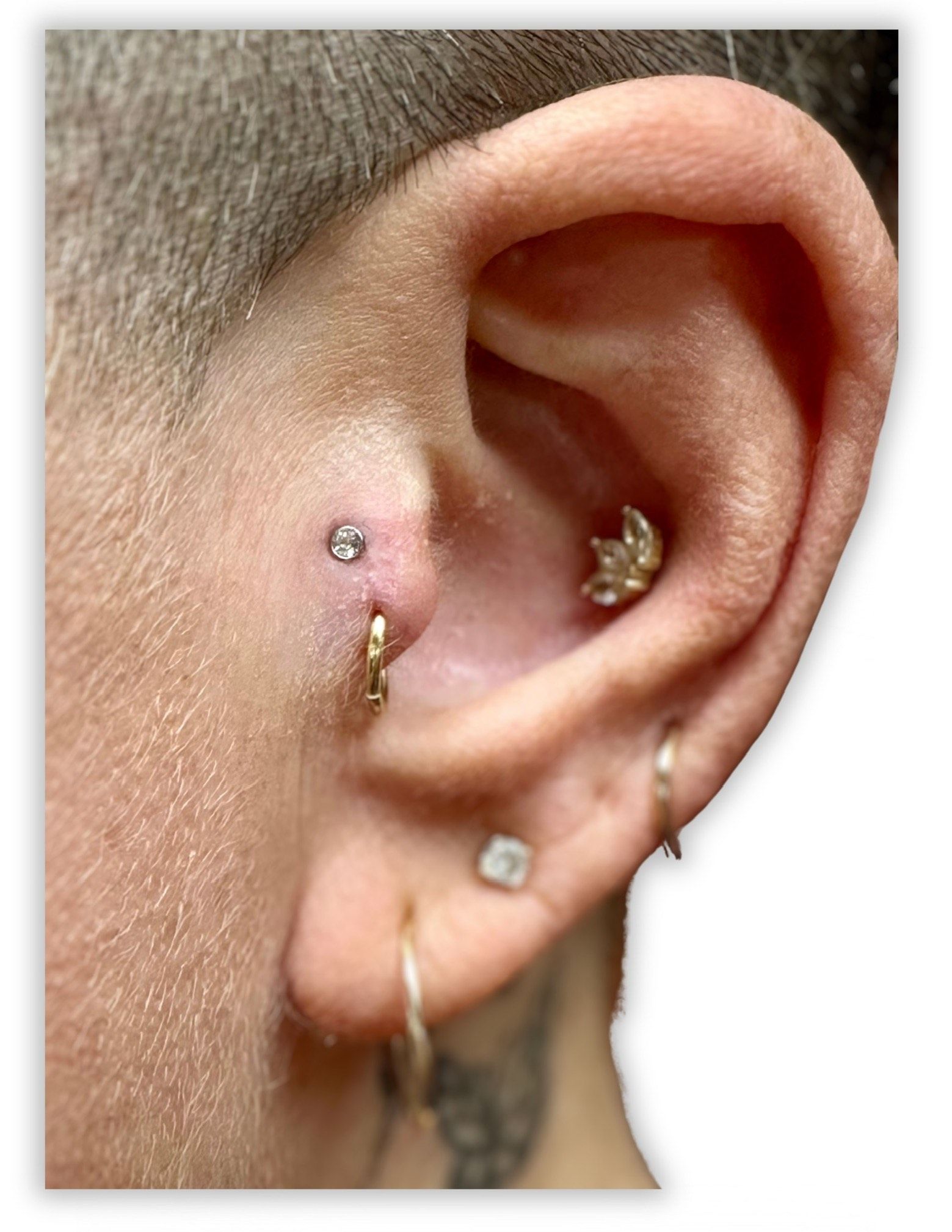 A close up of a person 's ear with multiple piercings