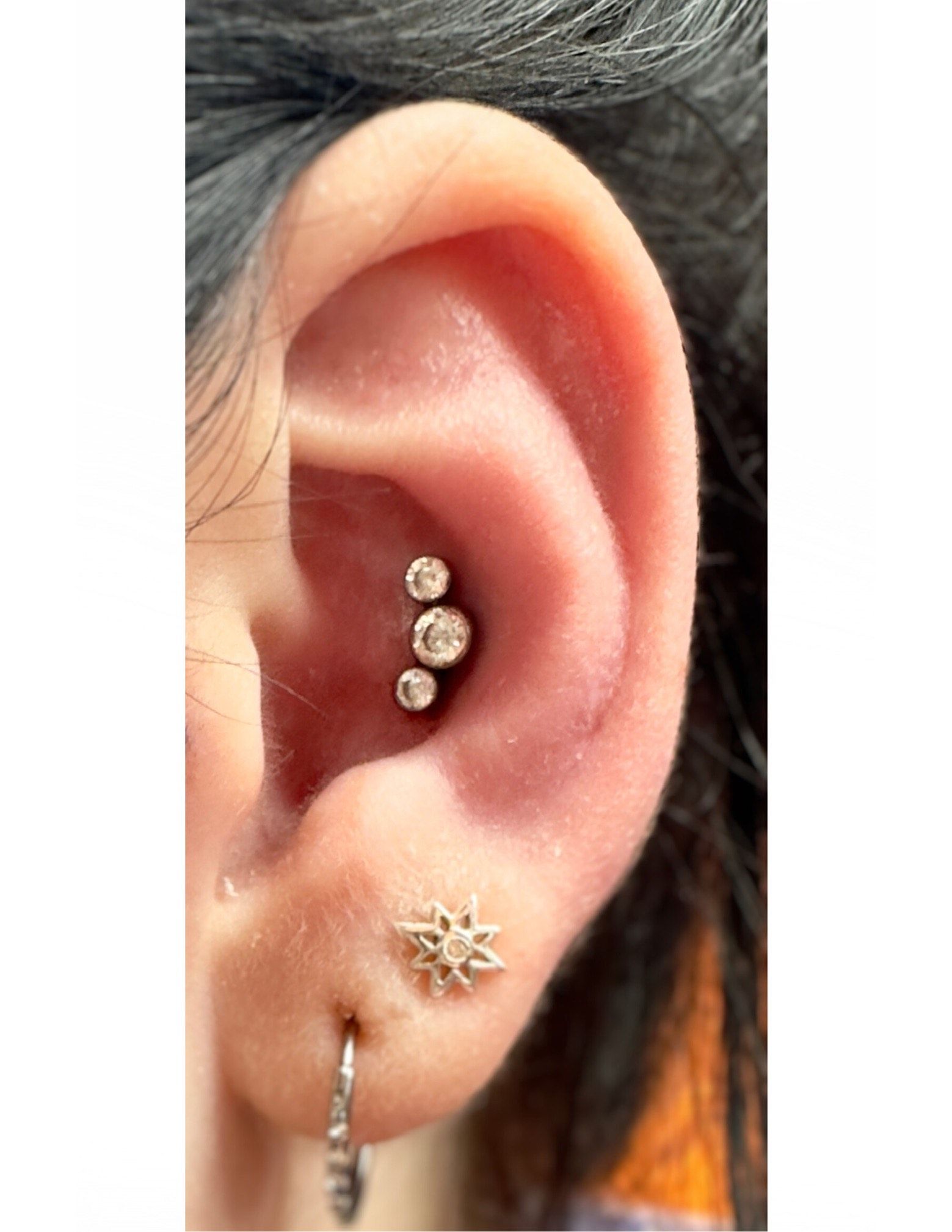 A close up of a woman 's ear with multiple piercings.