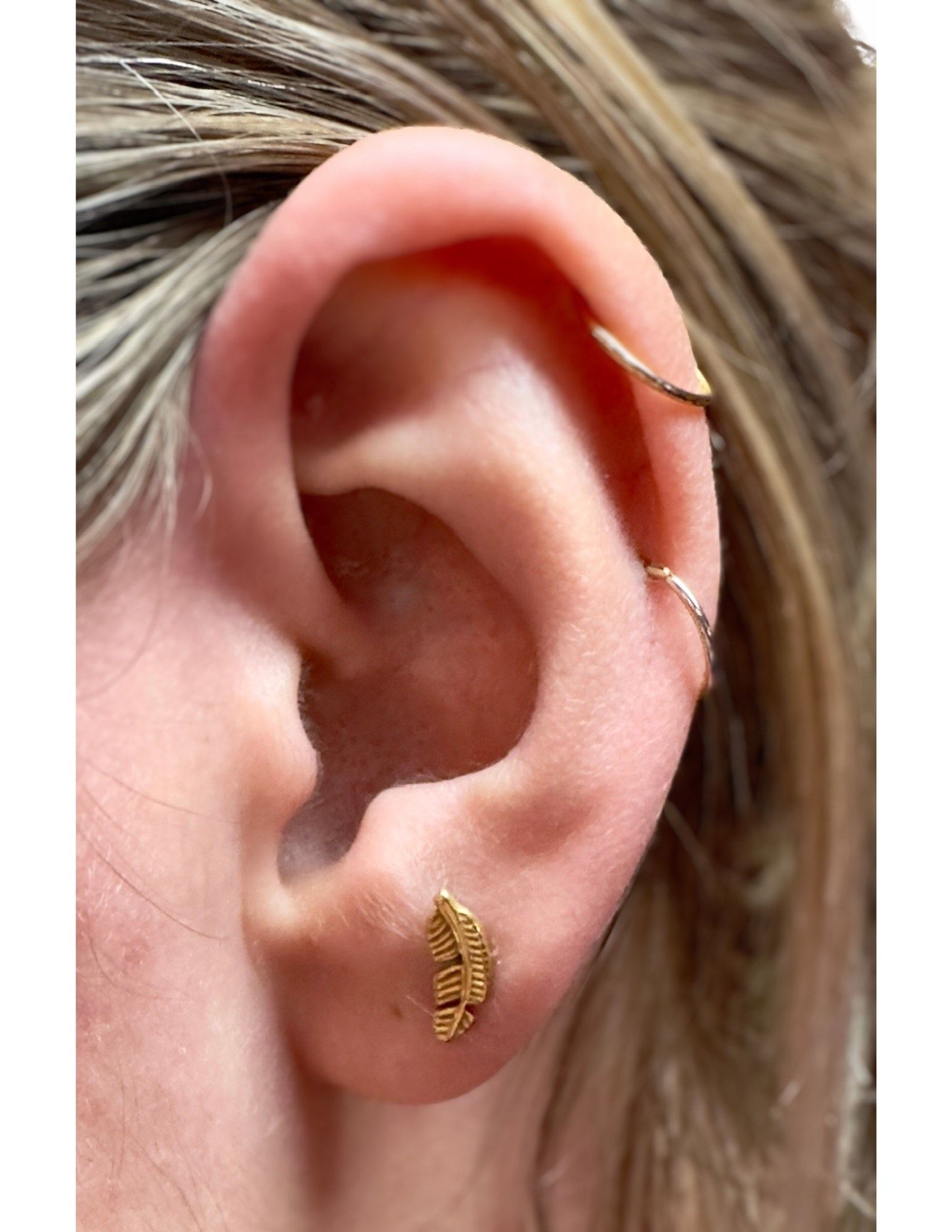 A close up of a woman 's ear with earrings and a piercing.