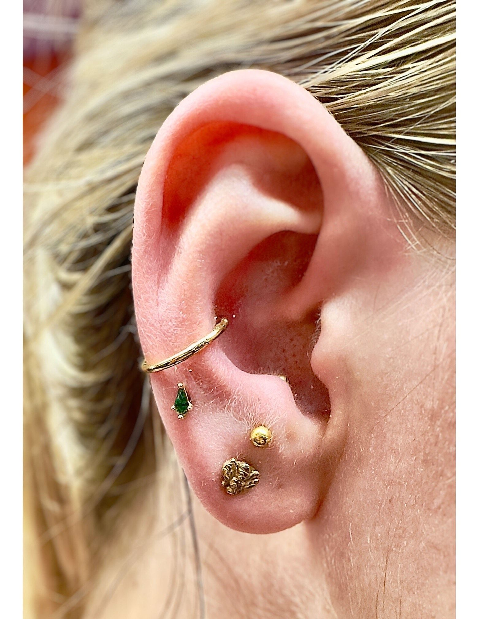 A close up of a woman 's ear with multiple piercings.