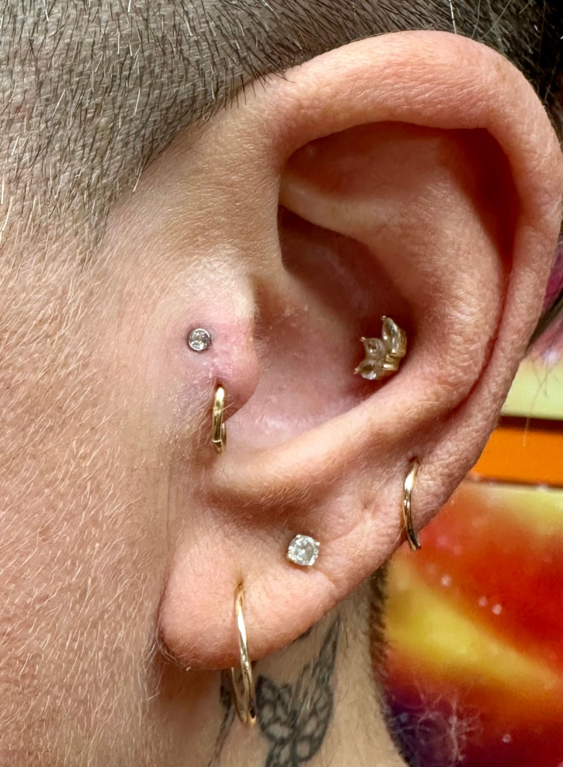 A close up of a person 's ear with multiple piercings.