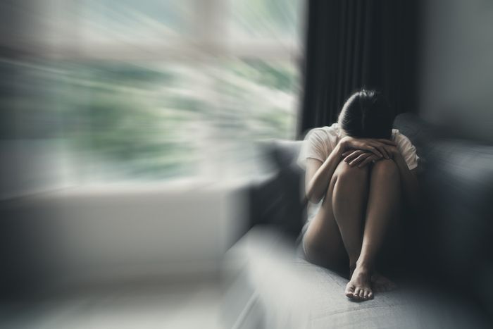 A woman is sitting on a couch with her head in her hands.