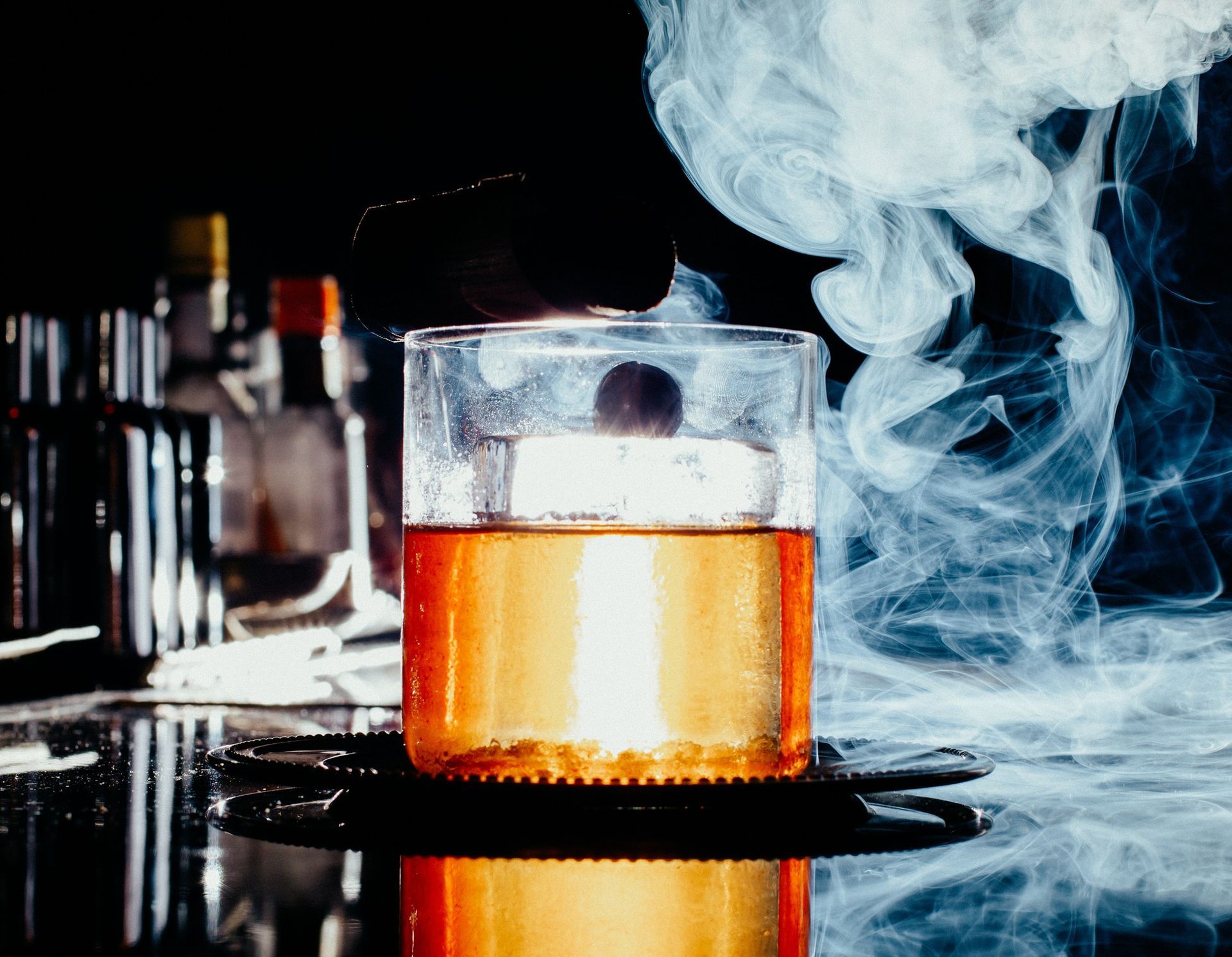 A close up of a glass of liquid with smoke coming out of it.