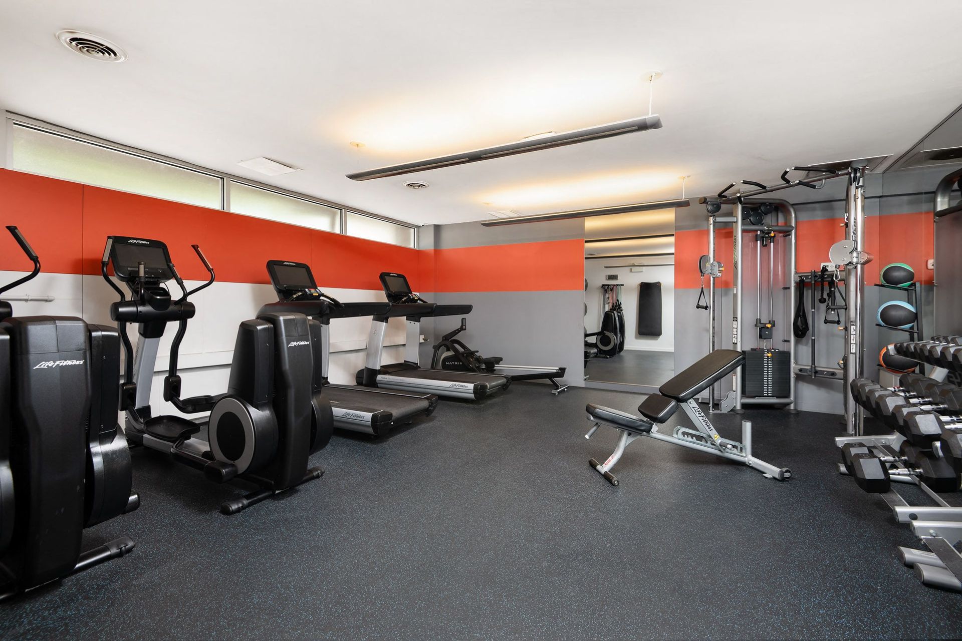 a gym with cardio equipment and weights on the floor