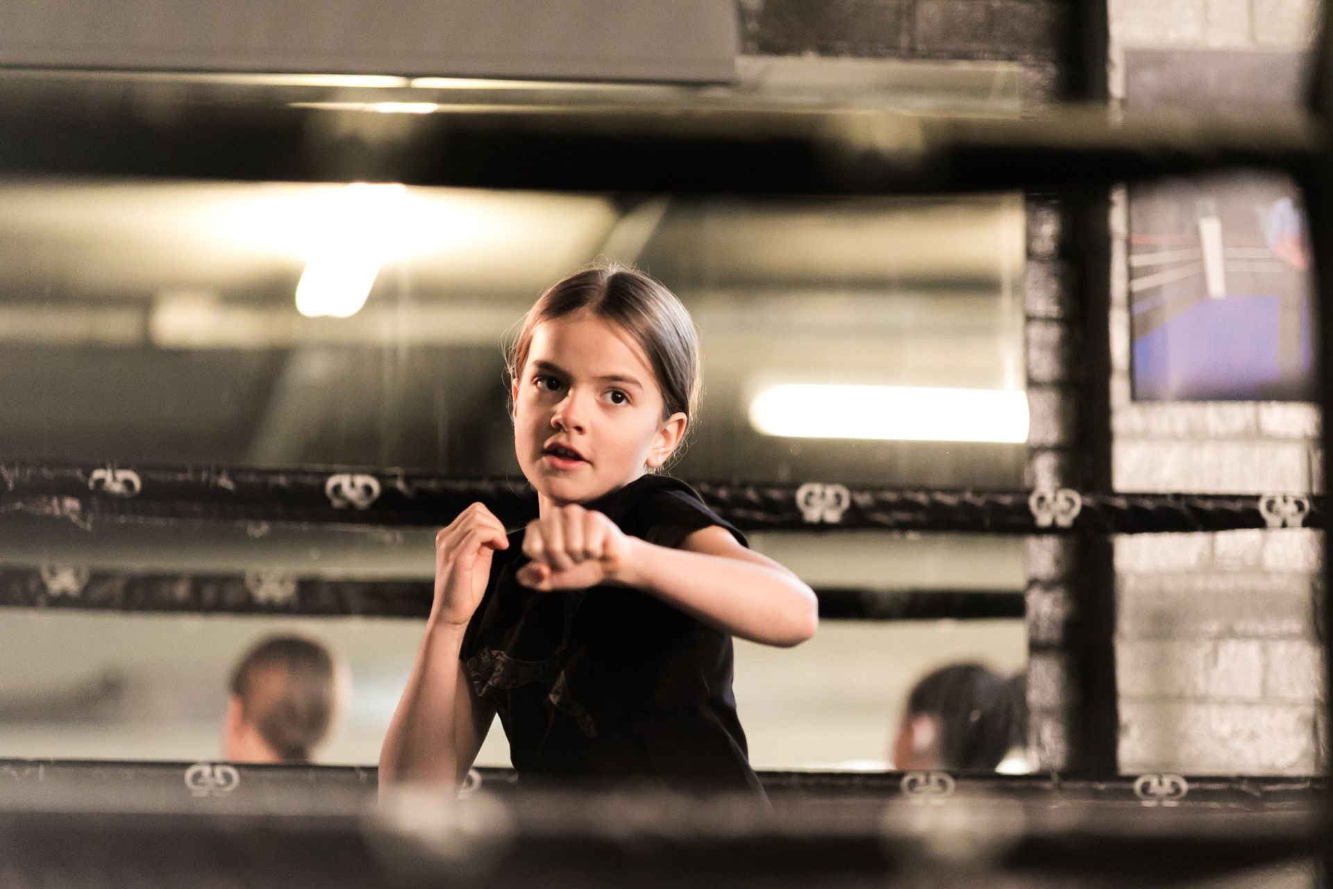 A young girl is standing in a boxing ring.