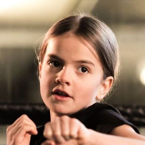 A little girl is wearing a black shirt and making a funny face.