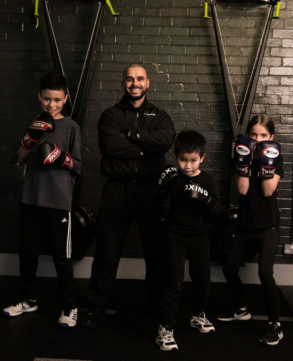 A man and three children wearing boxing gloves are posing for a picture.
