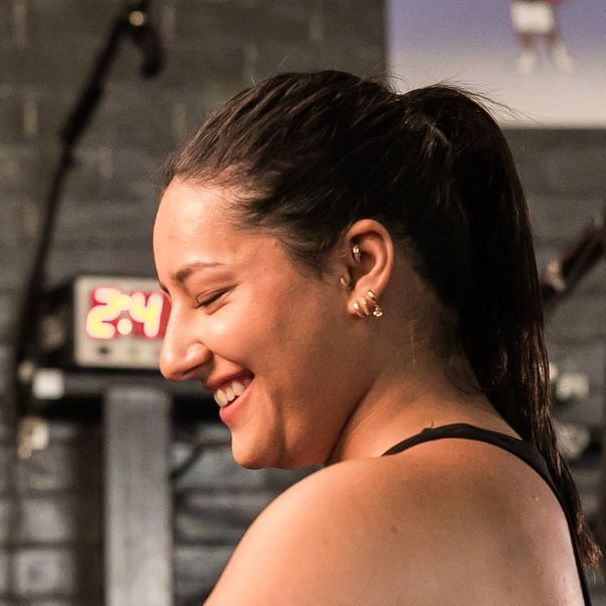 A woman is smiling in front of a sign that says 24