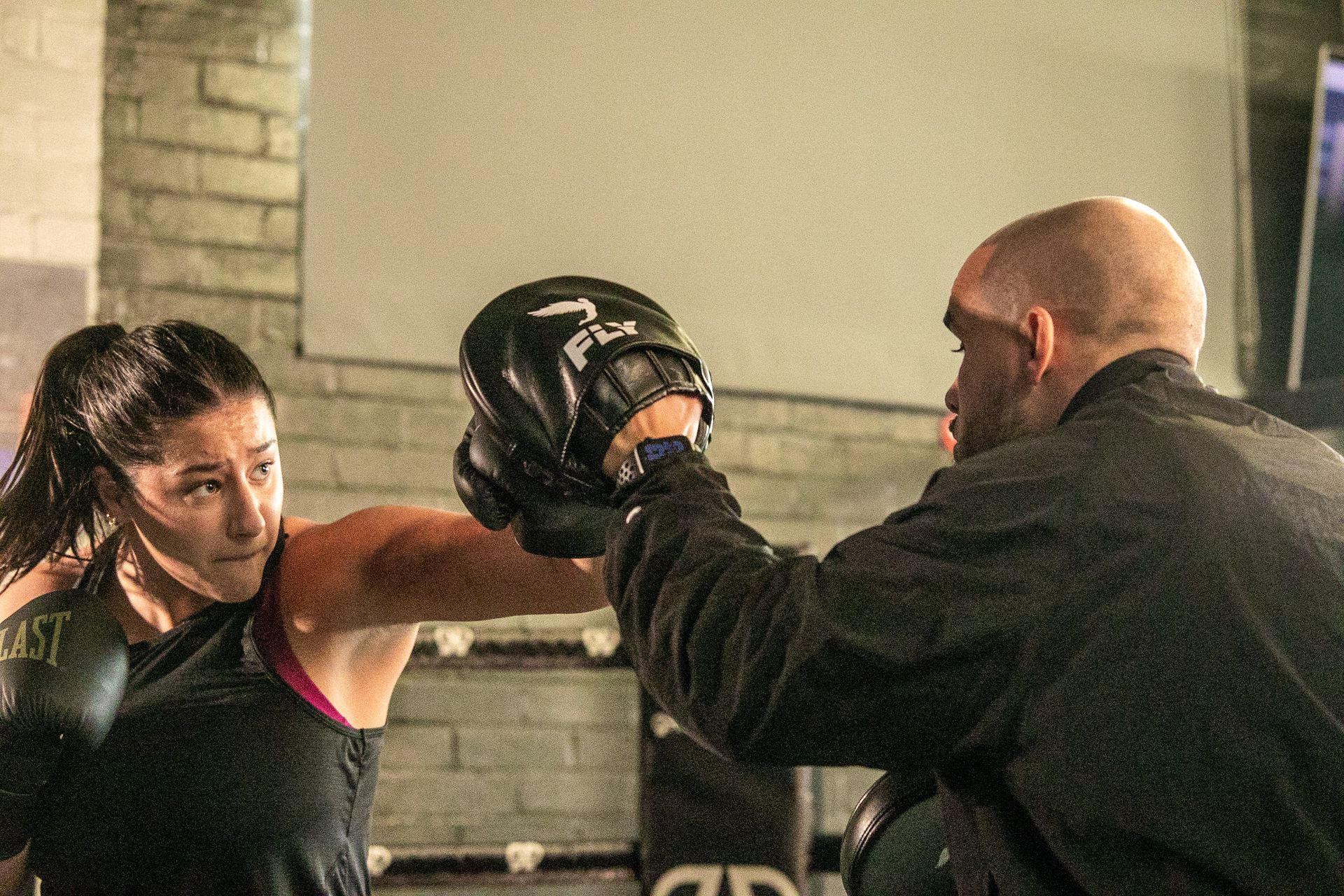Coach Femi and a woman are boxing in a gym.