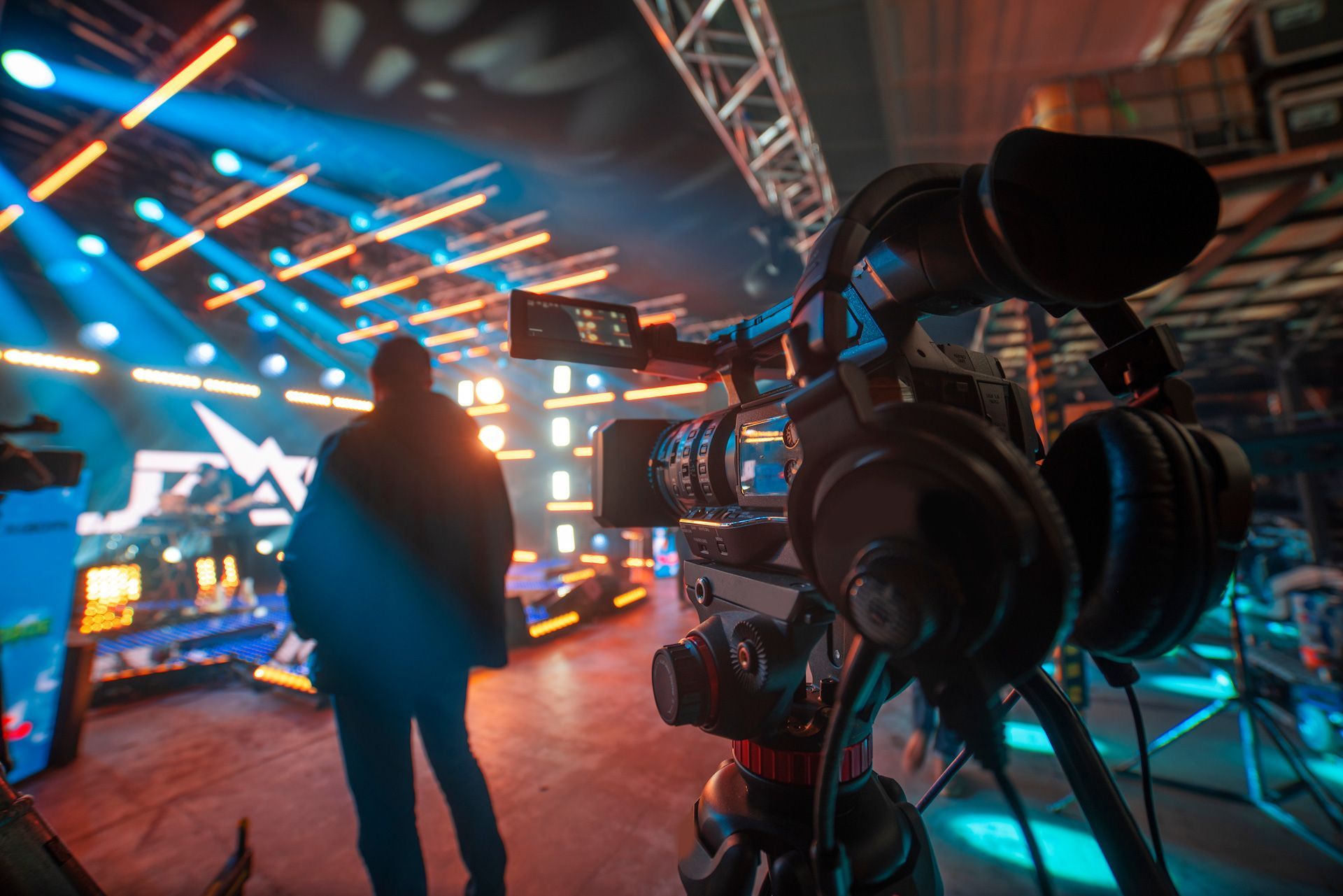 A man is standing in front of a camera in a dark room.