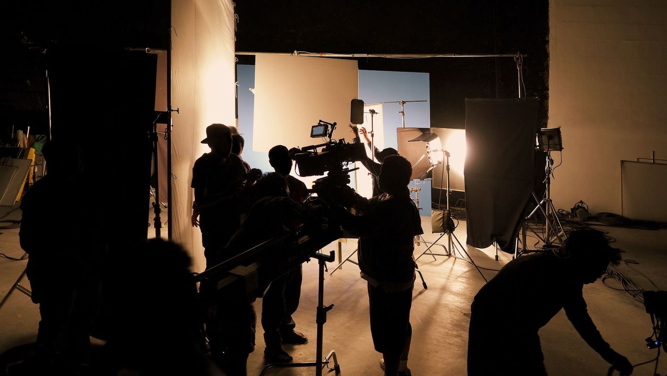 A group of people are standing around a camera in a dark room.
