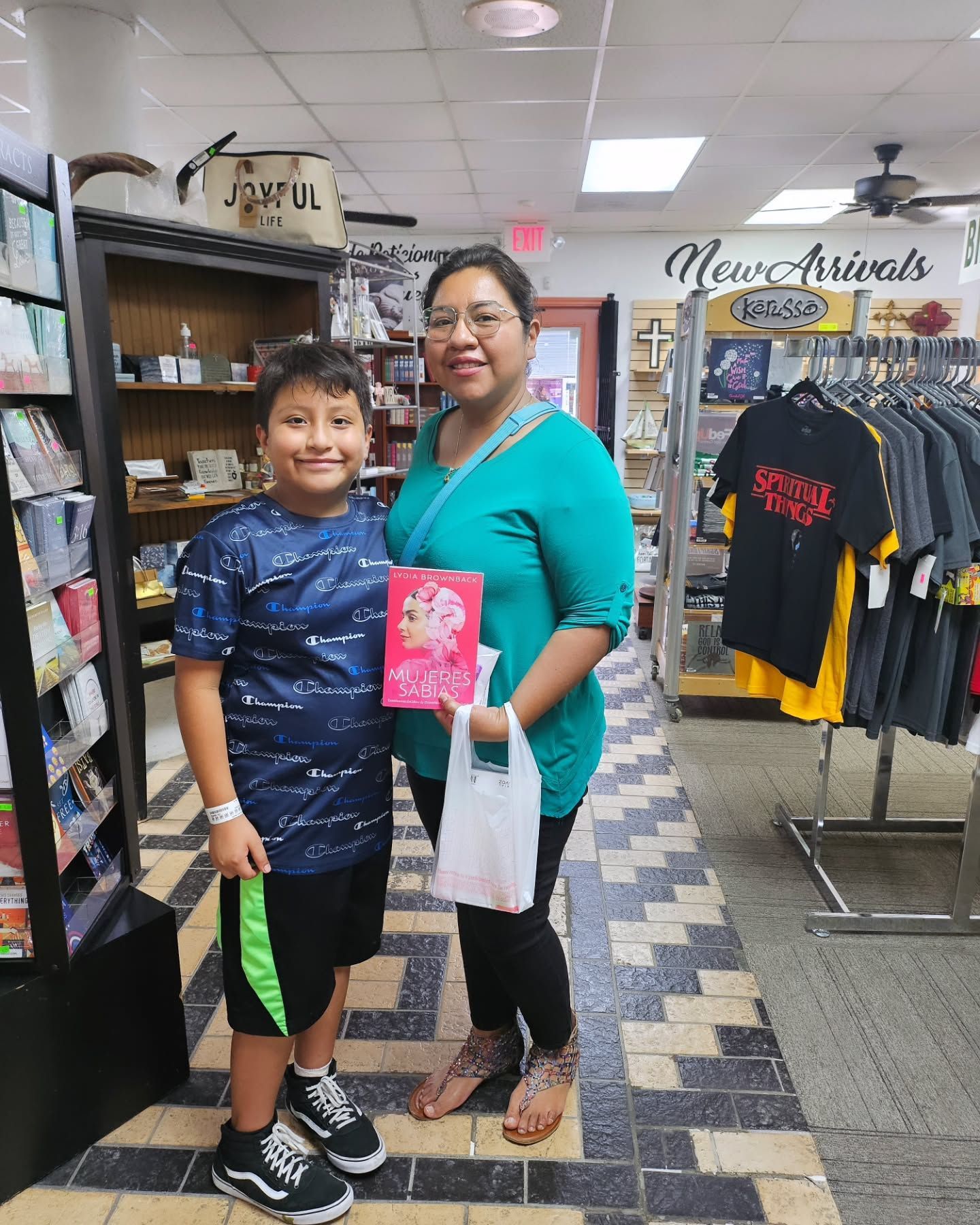 A woman and a child smiling, holding a book in a bookstore.