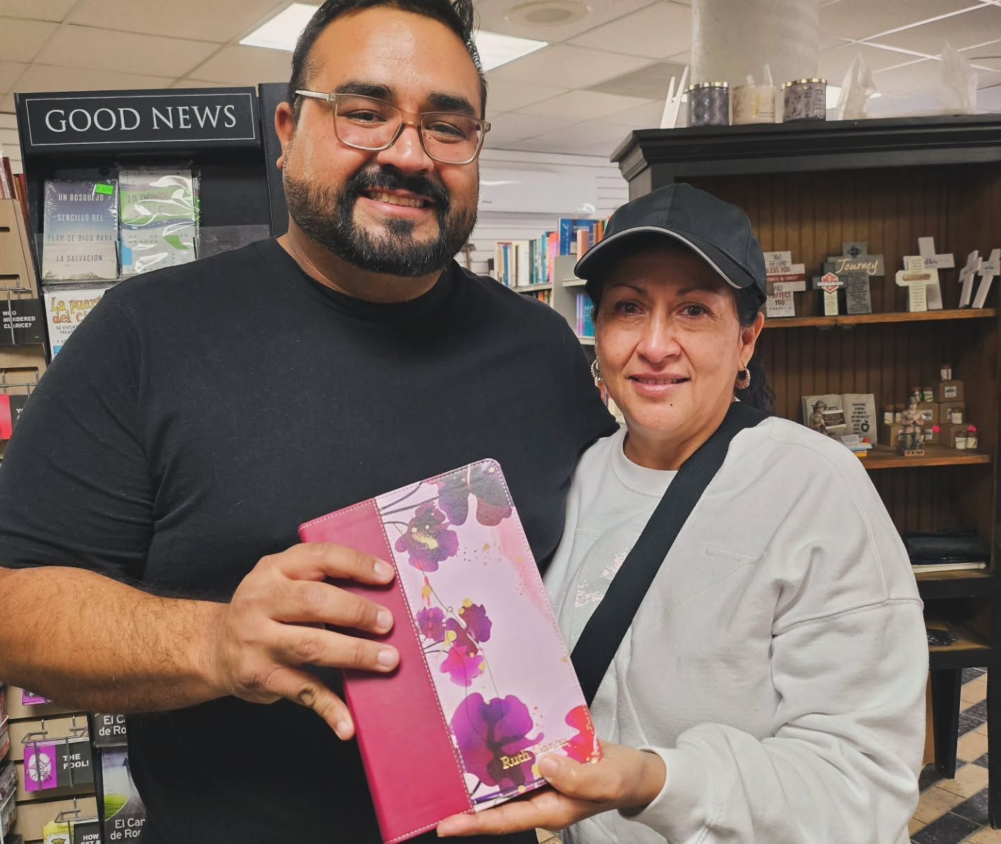 Two people holding a book with a floral cover in a bookstore.