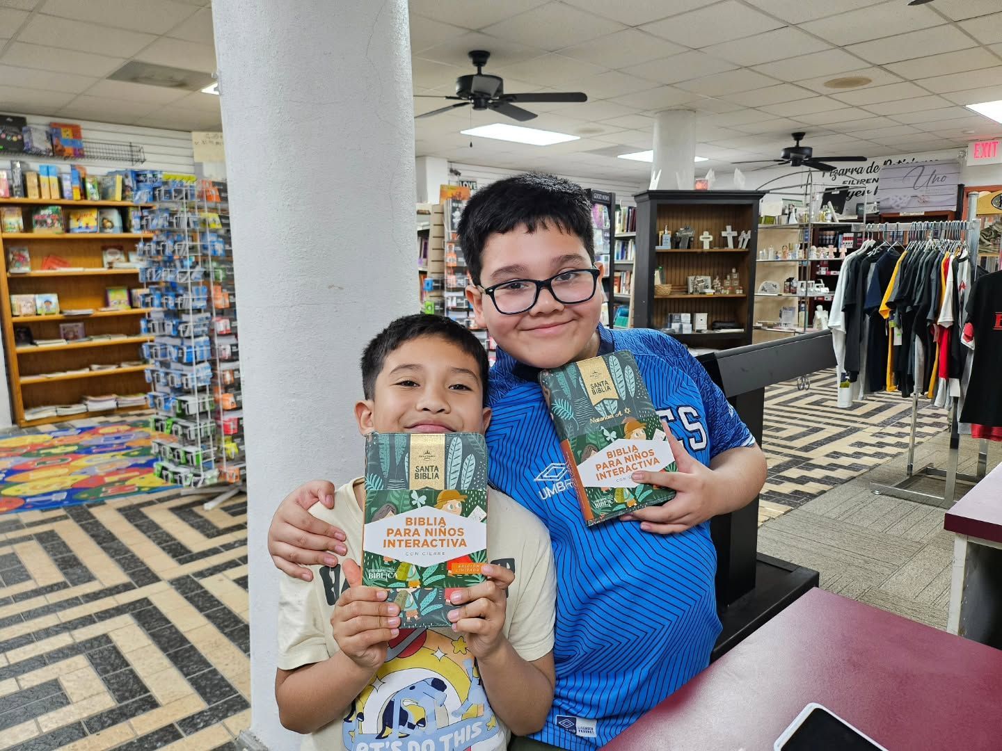 Two boys holding books, smiling in a bookstore.