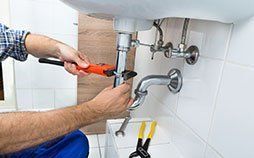 Hands of Plumber Fixing Pipes under sink