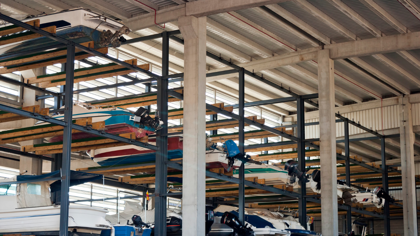 Factory interior with rows of machinery and yellow support beams under a high metal roof