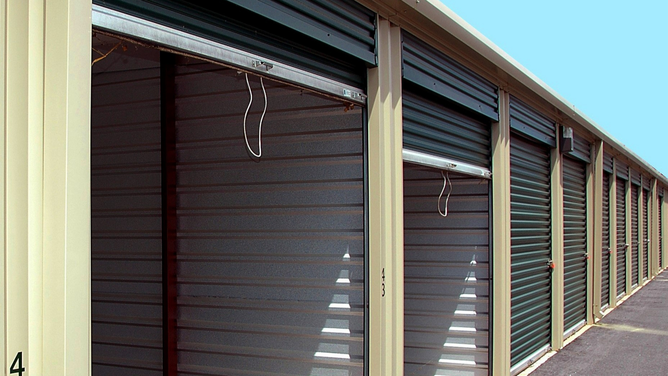 Empty metal storage unit with white corrugated walls and a concrete floor