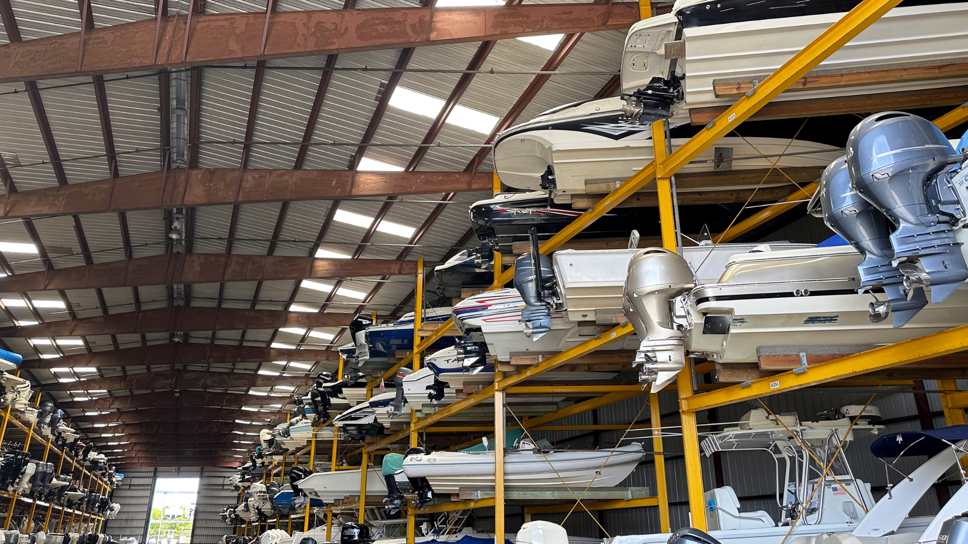 Factory interior with rows of machinery and yellow support beams under a high metal roof