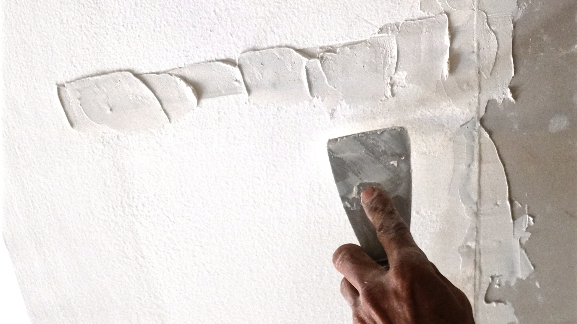 A person is plastering a wall with a spatula.