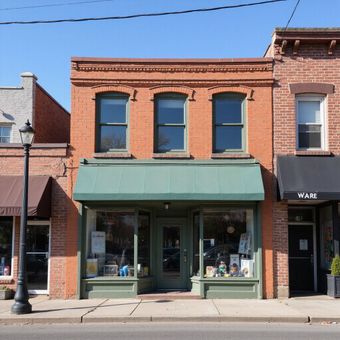 Red brick storefront with green awning and windows.