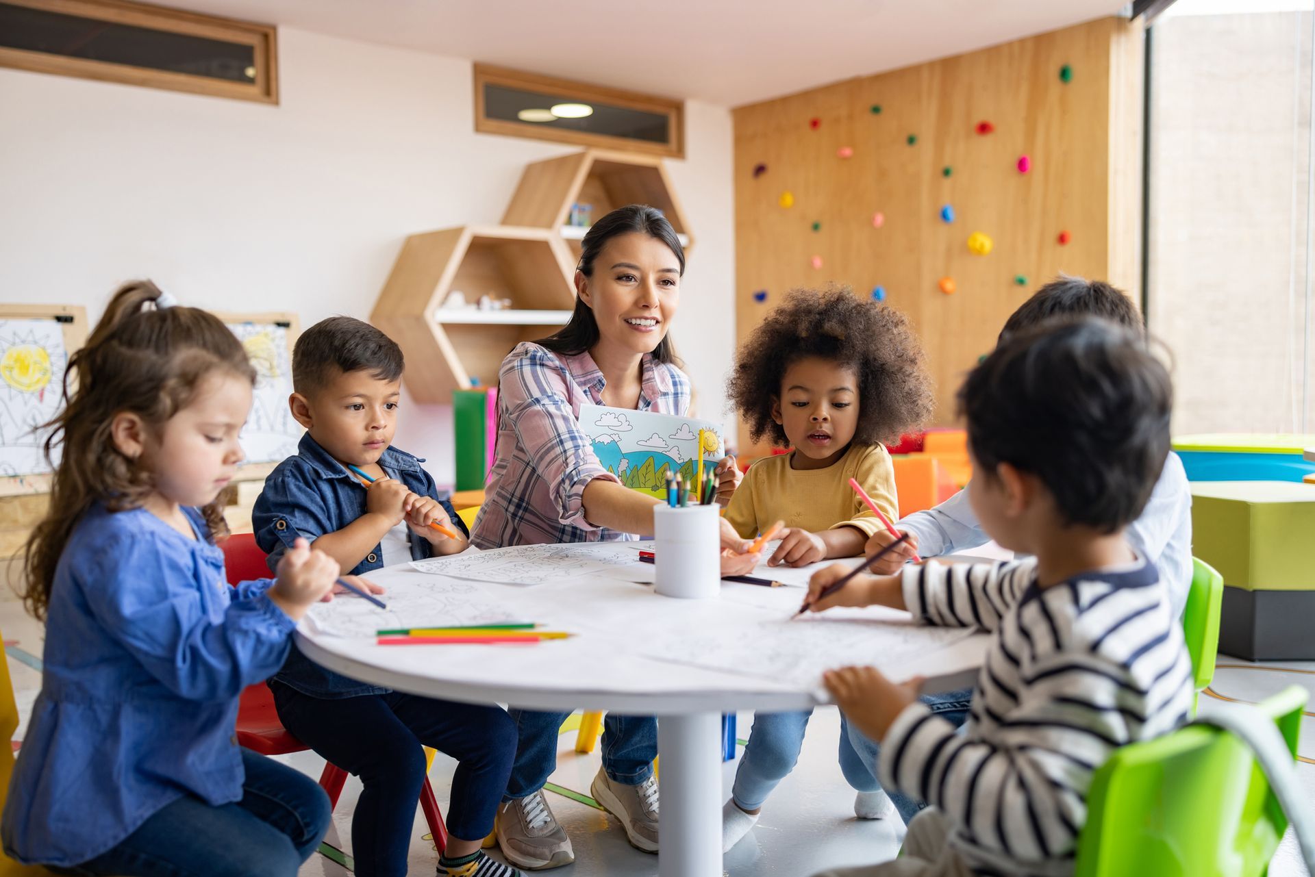 Group of children coloring in art class with the supervision of their teacher