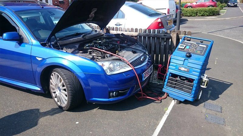 Blue car hooked up to engine diagnostic equipment