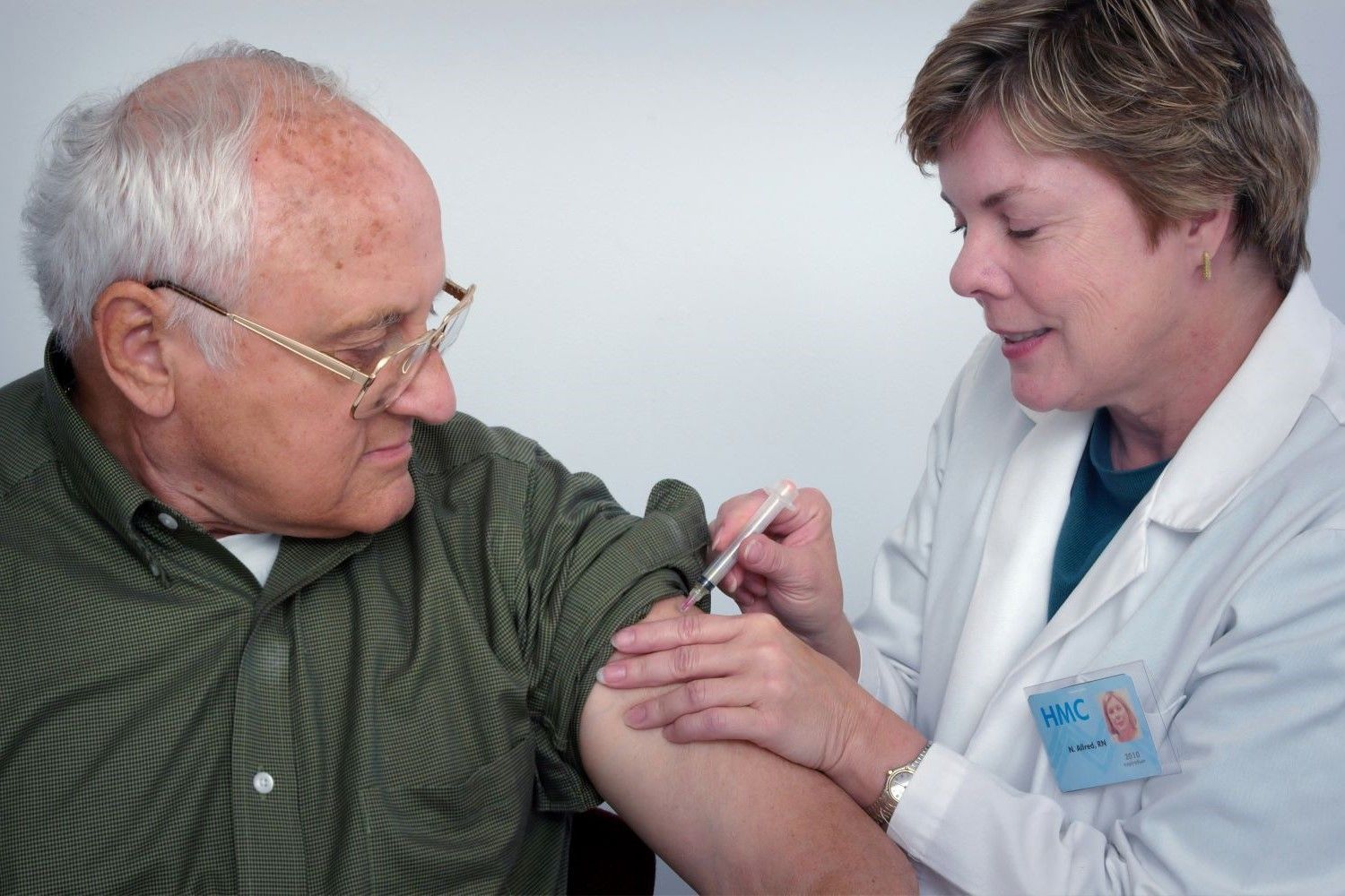 An older man is getting an injection from a female doctor.