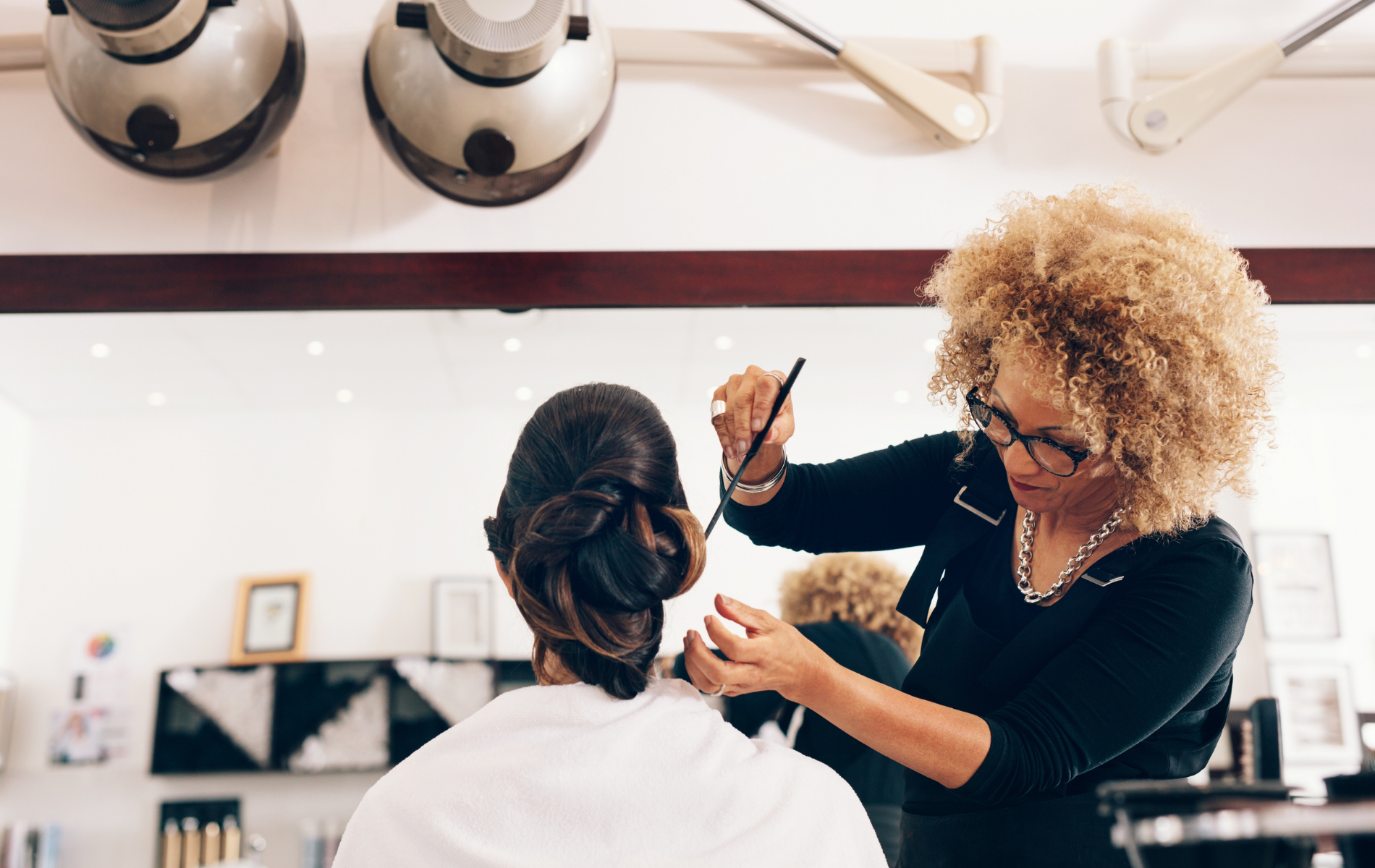 A woman is getting her hair done by a hairdresser in a salon.