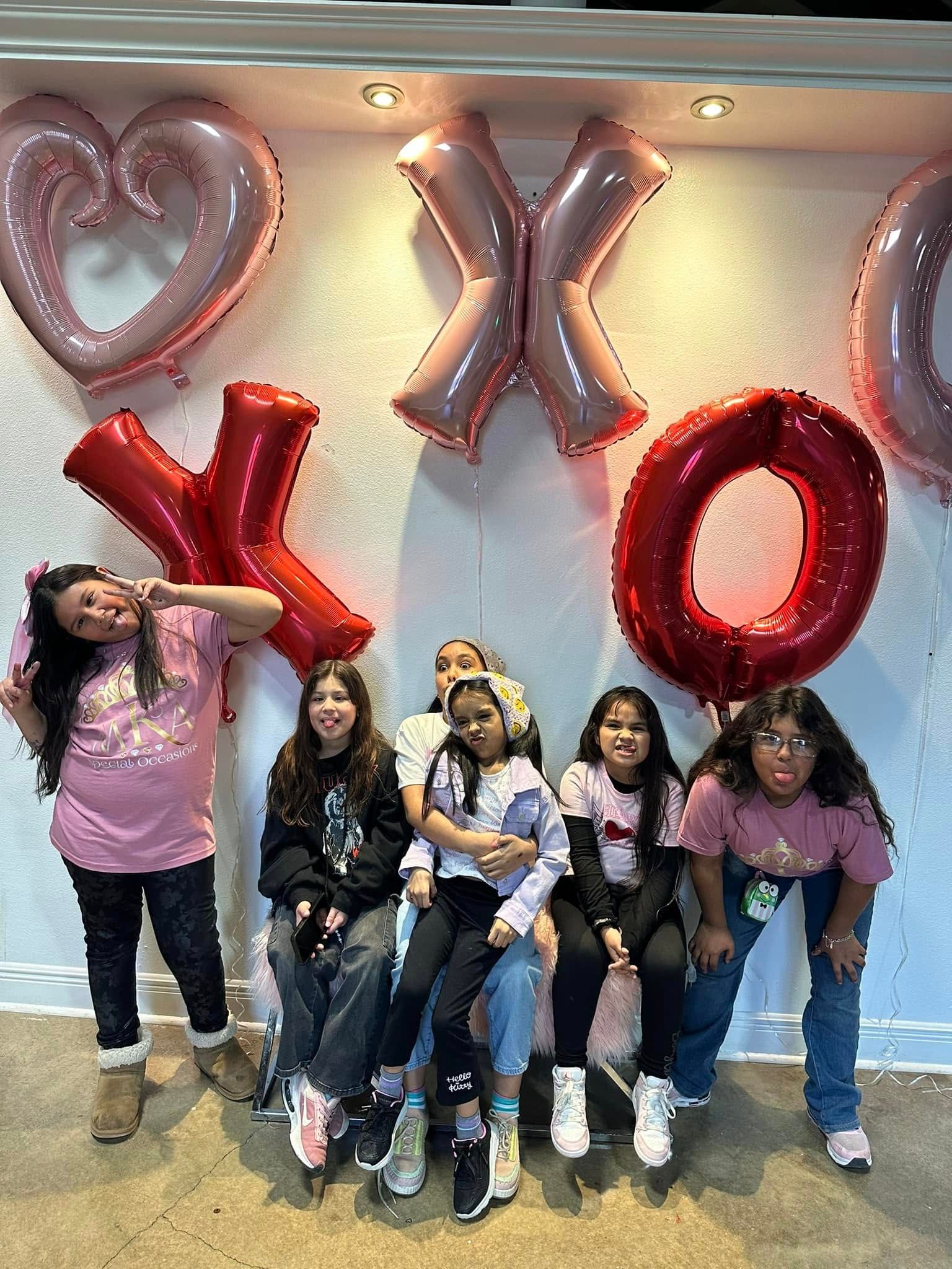 A group of women standing next to each other in front of balloons.