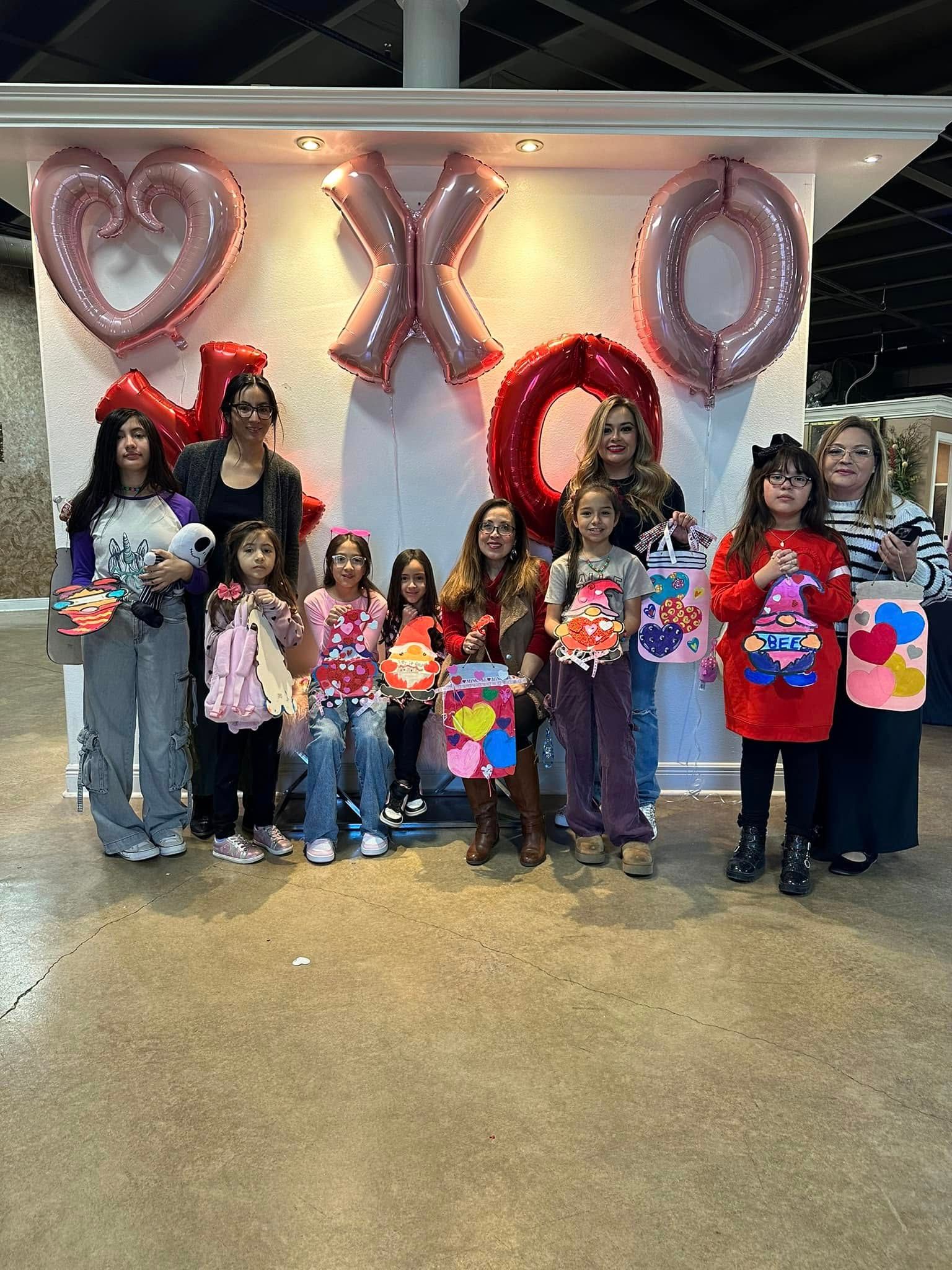 A group of young girls are posing for a picture in front of balloons.