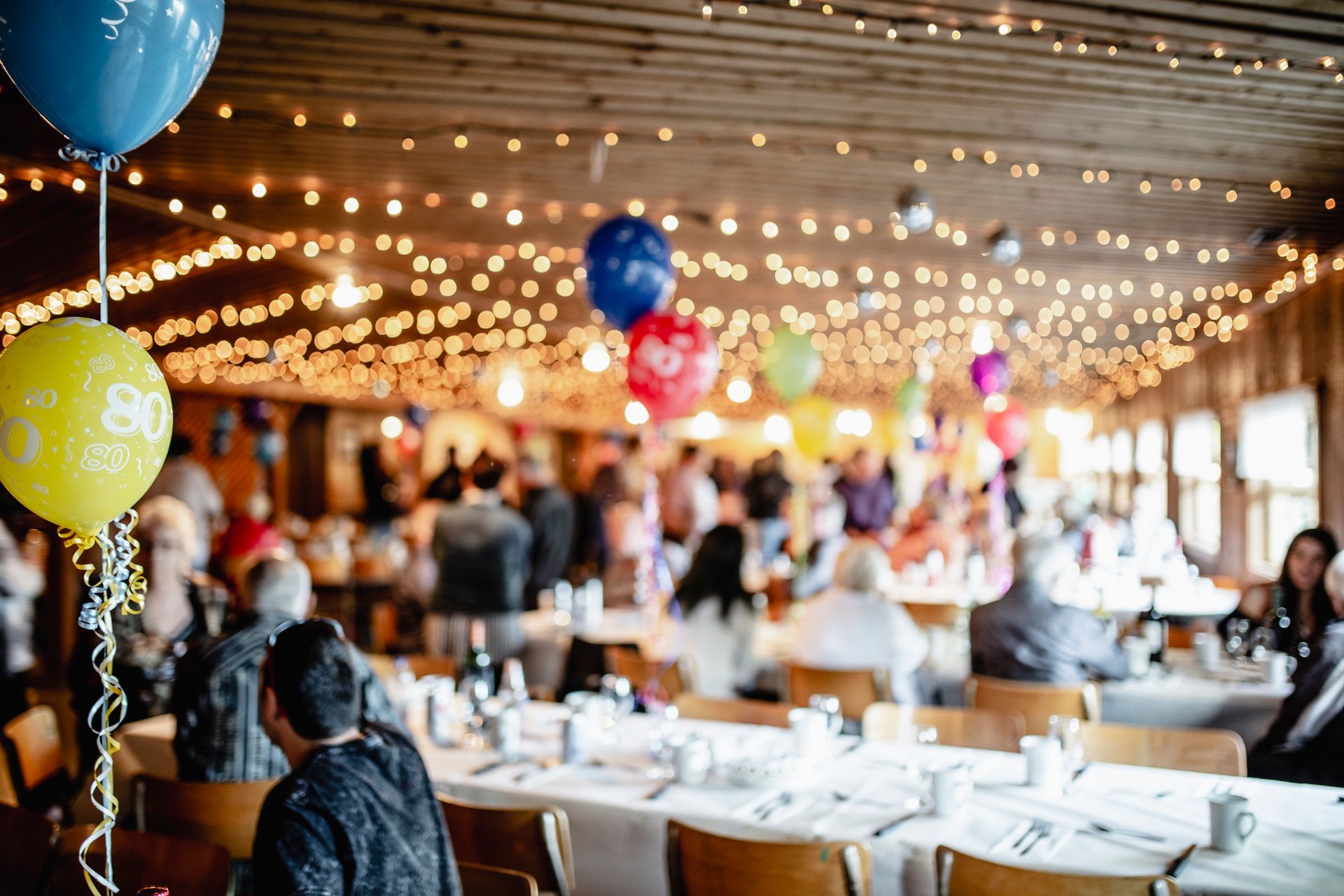 A group of people are sitting at tables at a birthday party.
