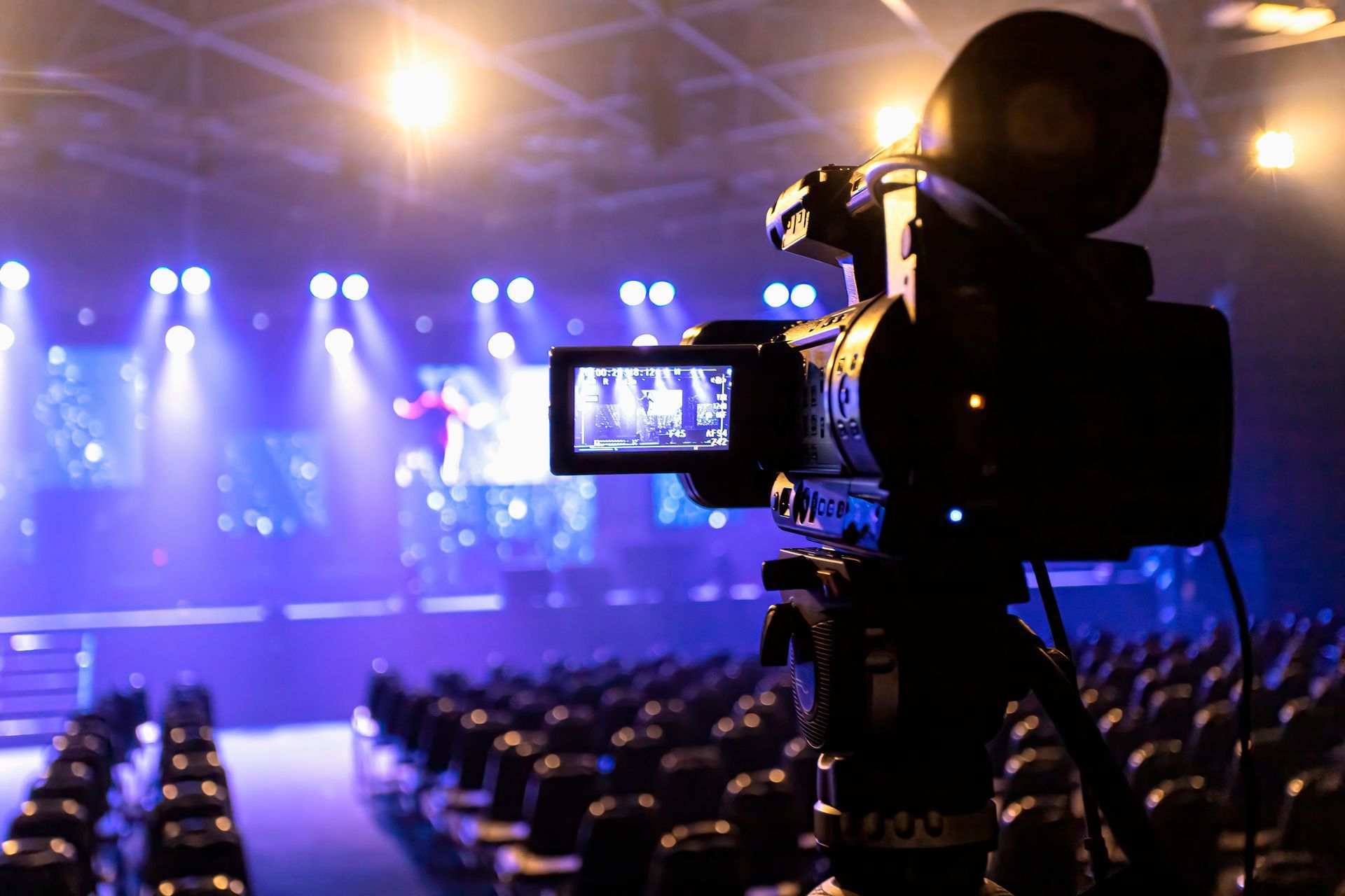 A video camera is recording a concert in a large auditorium.