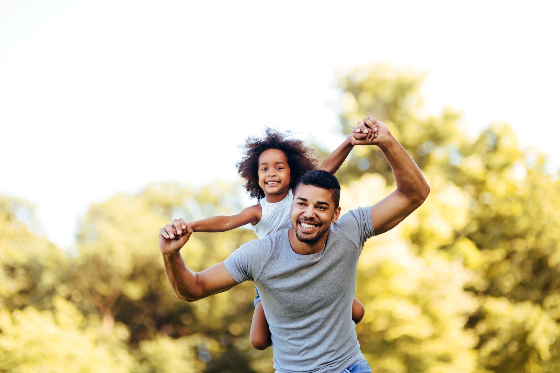 Father with young daughter on shoulders enjoying the outdoors together