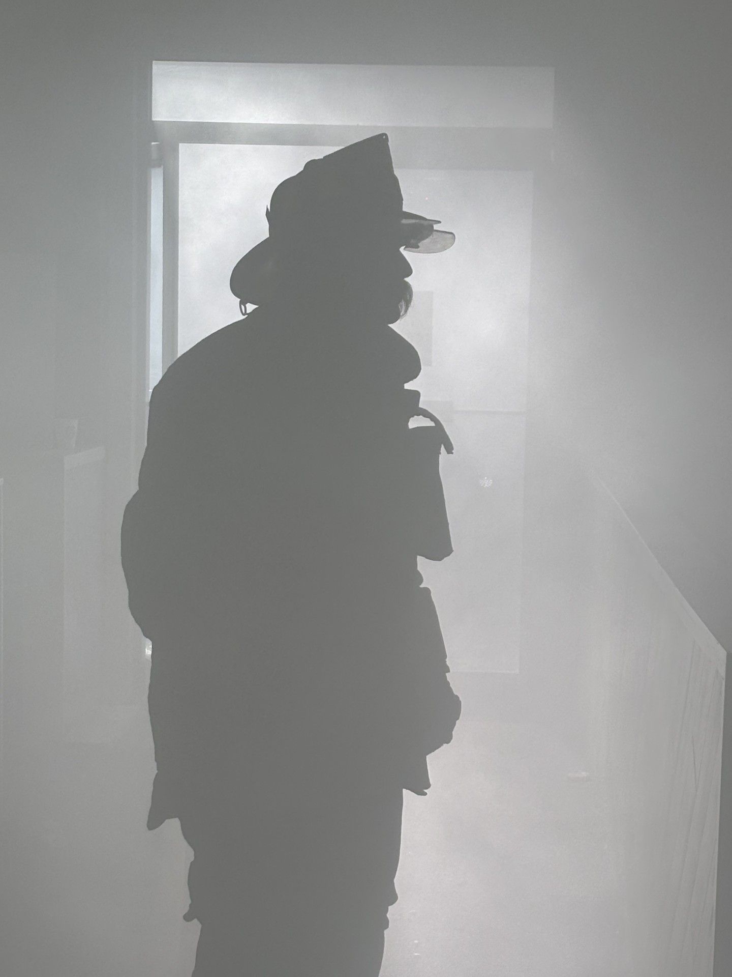 Firefighter in silhouette, obscured by smoke, standing in a doorway.