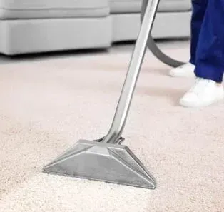 A person is using a vacuum cleaner to clean a carpet in a living room.