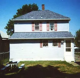 A white house with a gray roof and red shutters