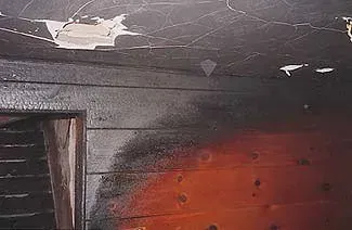 A room with a door and a ceiling that has been damaged by a fire.
