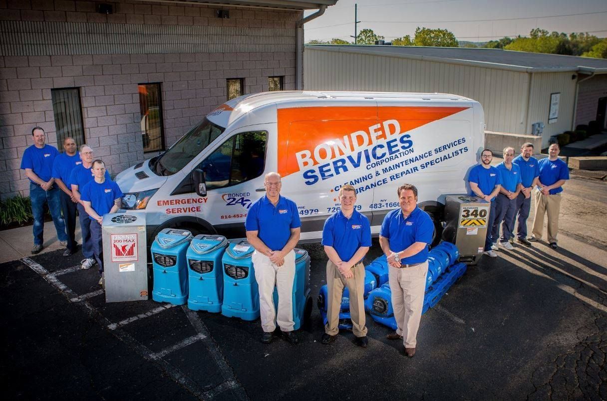A group of men are standing in front of a van that says bonded services.