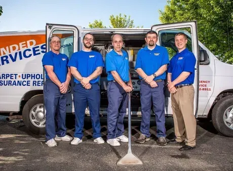 A group of men standing in front of a carpet cleaning van