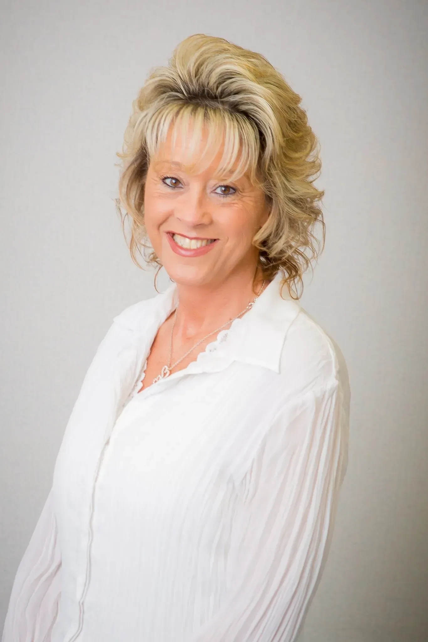 A woman in a white shirt is smiling for the camera.