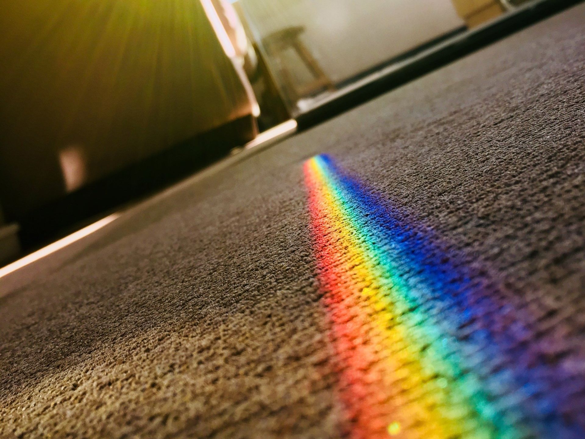 A rainbow is reflected on the floor of a room.