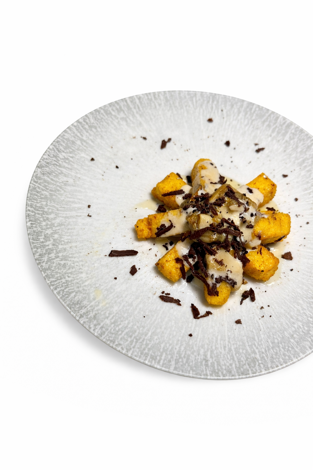 Gnocchi fritti dorati con salsa cremosa e scaglie di cioccolato fondente, serviti su un piatto d'argento decorativo.