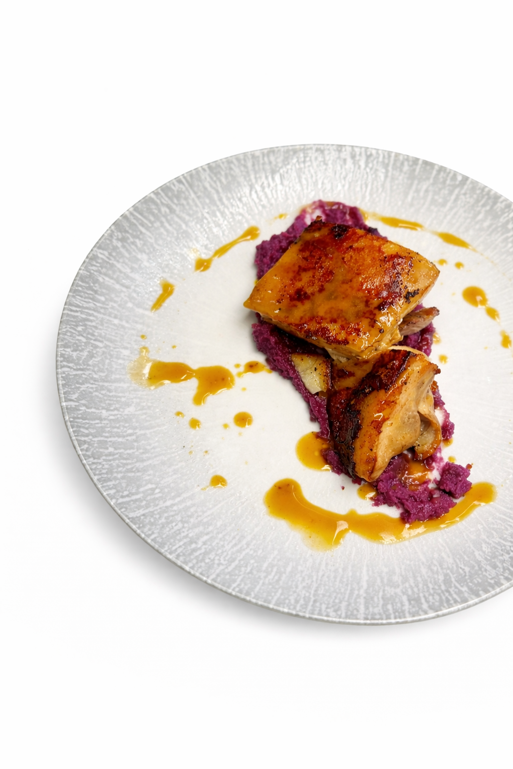 Piatto con pollo scottato su purè di patate viola e salsa a filo.
